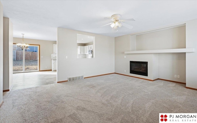 unfurnished living room featuring carpet, visible vents, baseboards, a glass covered fireplace, and ceiling fan with notable chandelier