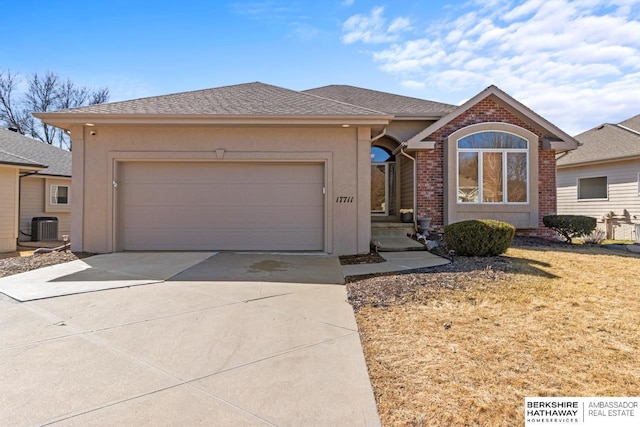 ranch-style home featuring stucco siding, central air condition unit, brick siding, and an attached garage