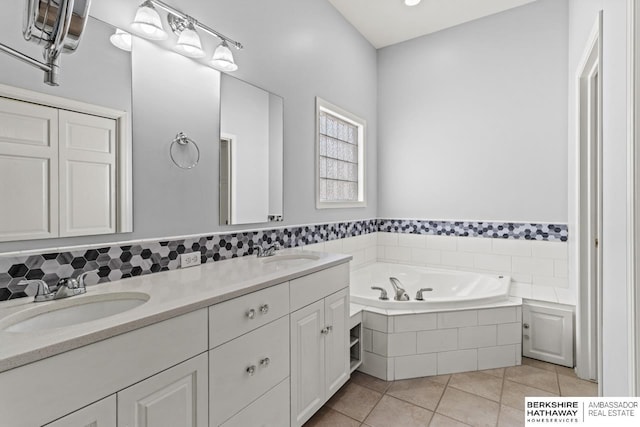 full bathroom with tile patterned floors, double vanity, a bath, and a sink