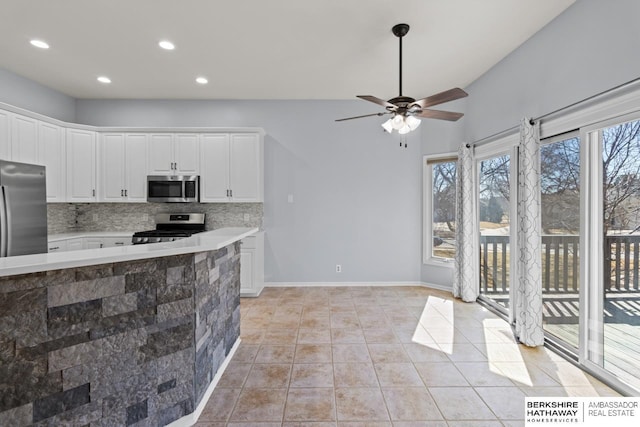 kitchen featuring decorative backsplash, appliances with stainless steel finishes, white cabinetry, and light countertops