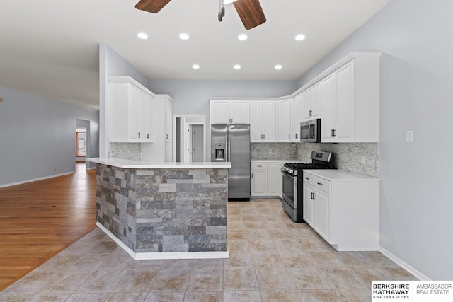 kitchen featuring a ceiling fan, backsplash, stainless steel appliances, a peninsula, and light countertops