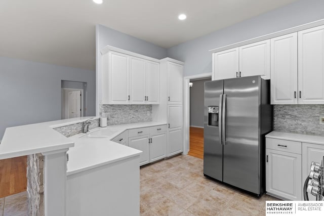 kitchen with white cabinetry, a peninsula, stainless steel refrigerator with ice dispenser, and a sink