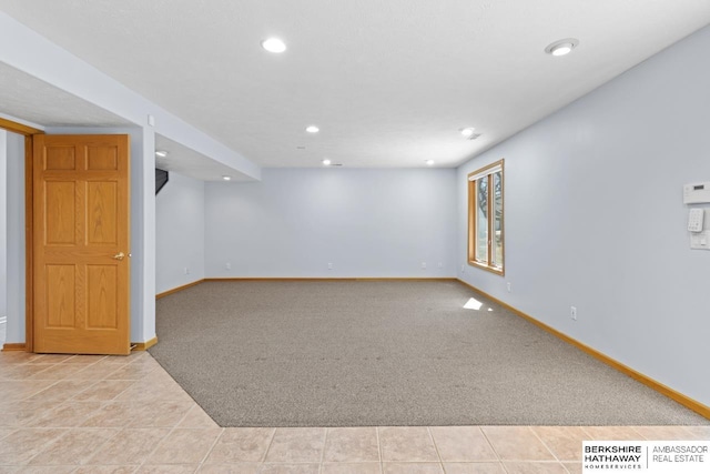 spare room featuring light carpet, light tile patterned floors, recessed lighting, and baseboards