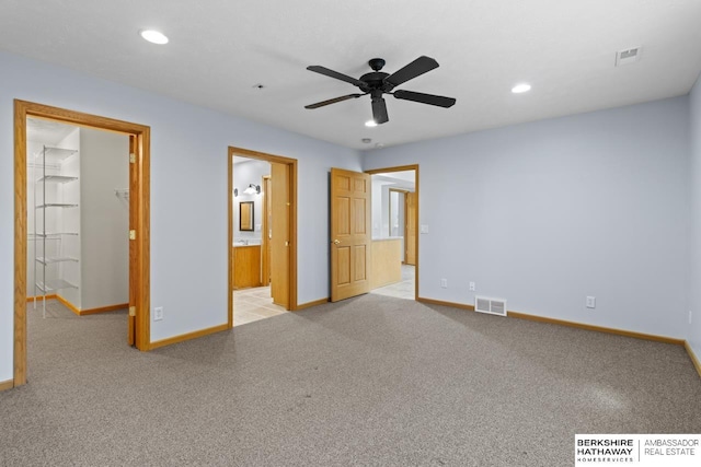 unfurnished bedroom with a walk in closet, recessed lighting, light colored carpet, and visible vents