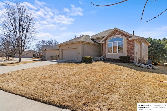 single story home featuring a front yard, a garage, brick siding, and driveway