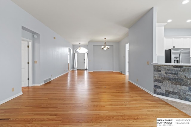 unfurnished living room featuring light wood-type flooring, visible vents, recessed lighting, baseboards, and a chandelier