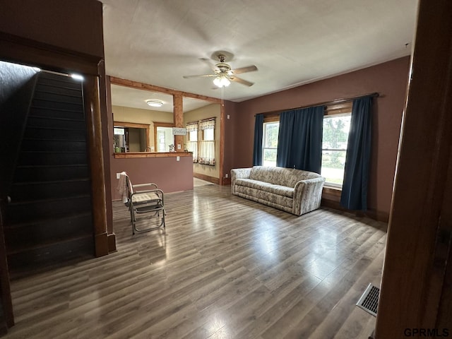 living area featuring visible vents, baseboards, a ceiling fan, and wood finished floors