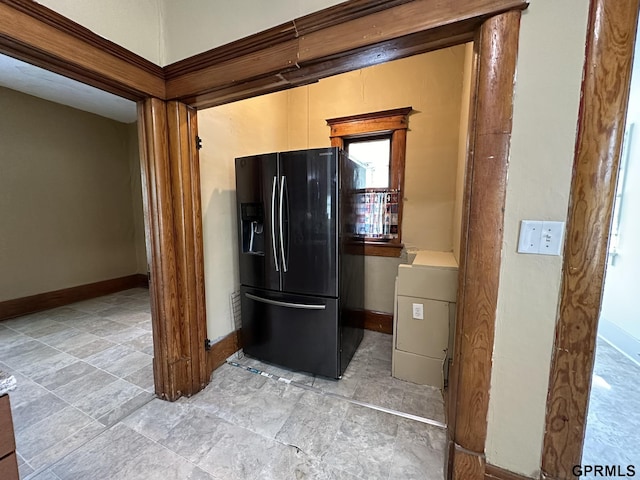 kitchen featuring baseboards and black fridge