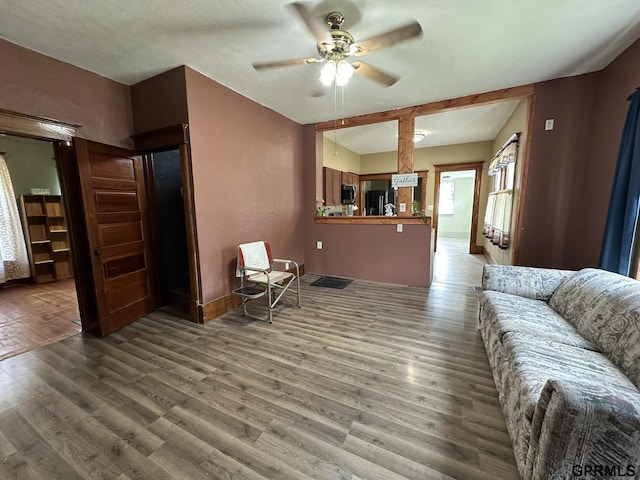 living room featuring ceiling fan, baseboards, and wood finished floors