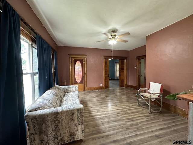 living area with ceiling fan, baseboards, and wood finished floors