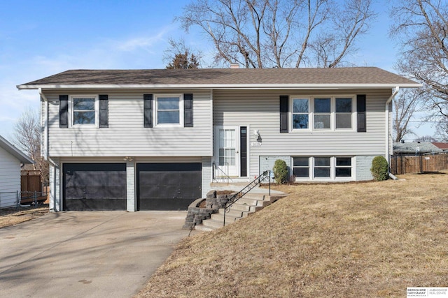 raised ranch featuring an attached garage, concrete driveway, a front lawn, and fence