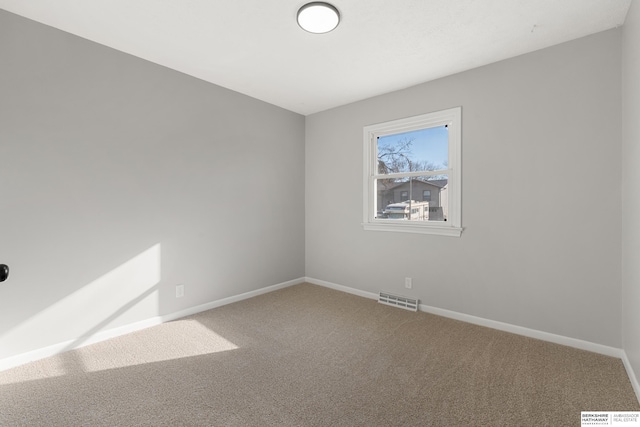 spare room with carpet flooring, baseboards, and visible vents