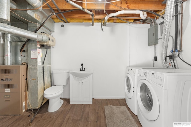 washroom featuring washer and clothes dryer, electric panel, laundry area, wood finished floors, and a sink