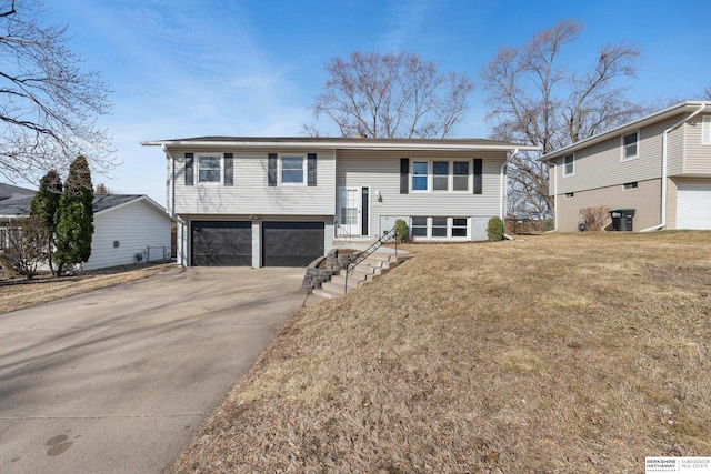 split foyer home featuring concrete driveway, an attached garage, and a front lawn