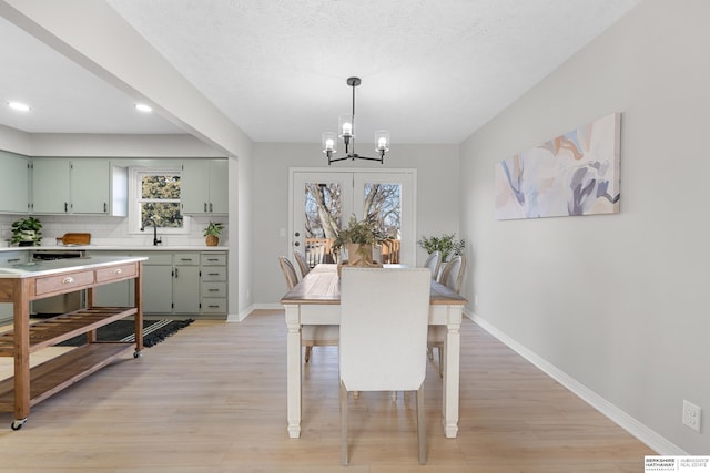 dining room featuring baseboards, light wood-style flooring, recessed lighting, a textured ceiling, and a notable chandelier