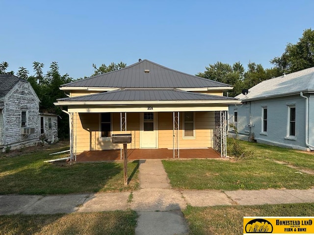 bungalow with a porch, metal roof, and a front lawn