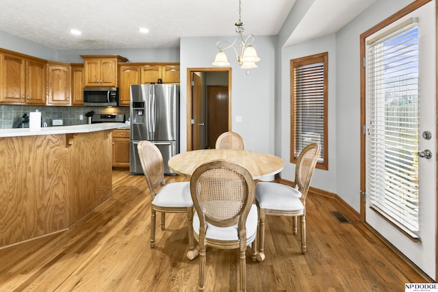 interior space featuring light wood-type flooring, visible vents, baseboards, and a chandelier