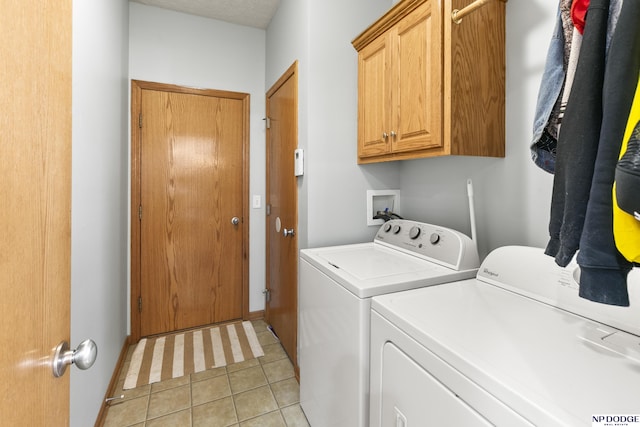 clothes washing area featuring light tile patterned floors, cabinet space, and washing machine and clothes dryer