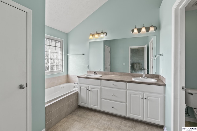 full bath featuring toilet, a garden tub, double vanity, lofted ceiling, and a sink