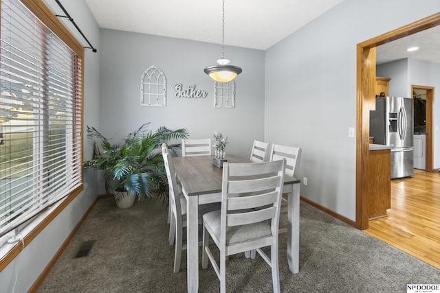 dining area with visible vents, baseboards, light colored carpet, and light wood finished floors