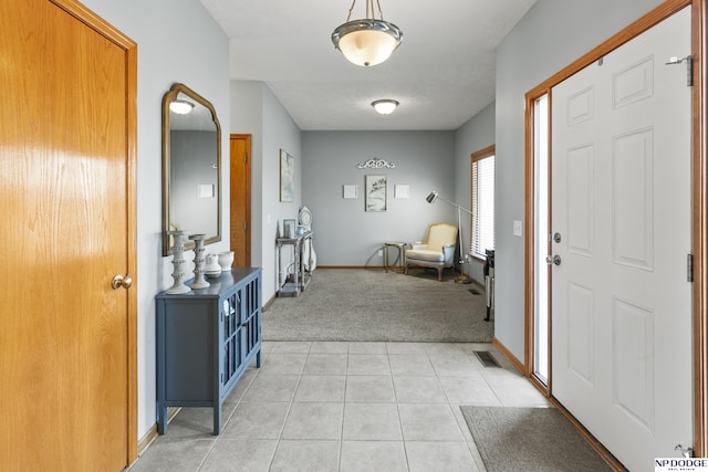 entryway featuring light tile patterned floors, visible vents, baseboards, and light colored carpet