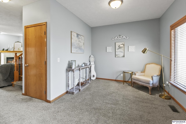 living area featuring carpet flooring, a fireplace, visible vents, and baseboards