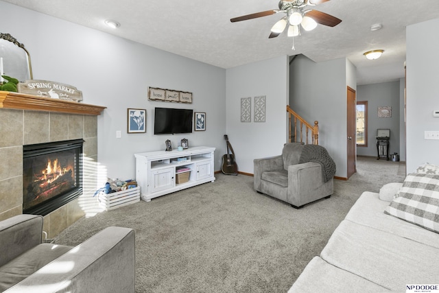 living room with a textured ceiling, stairway, carpet floors, and a tile fireplace