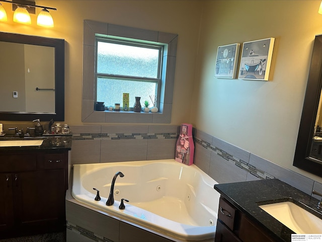 bathroom with two vanities, a tub with jets, and a sink