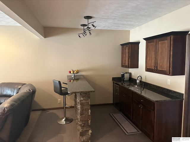 interior space with dark tile patterned floors, baseboards, and a sink