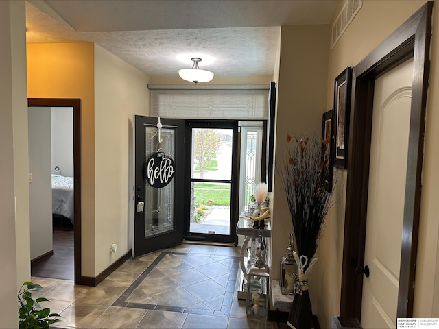 tiled entrance foyer with visible vents, baseboards, and a textured ceiling