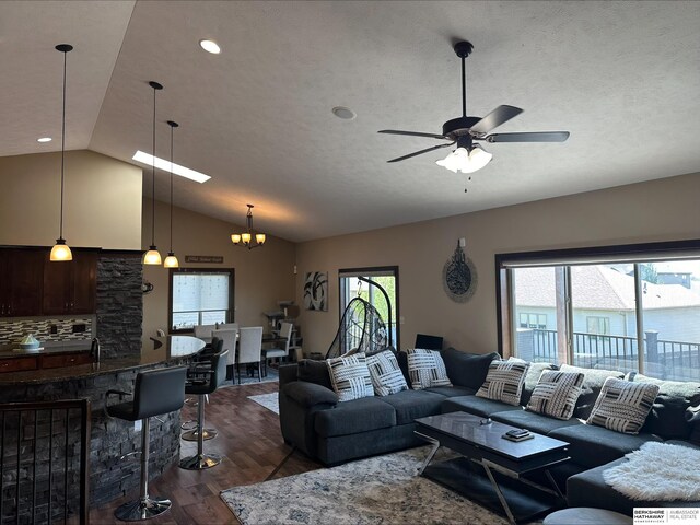 living area featuring lofted ceiling, recessed lighting, dark wood-style flooring, a textured ceiling, and ceiling fan with notable chandelier