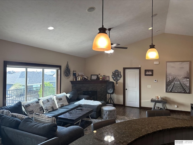 living room featuring a ceiling fan, baseboards, dark wood finished floors, a stone fireplace, and vaulted ceiling