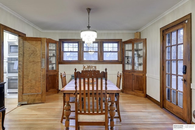 dining room with a chandelier, light wood-style flooring, and ornamental molding