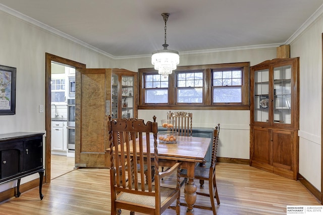 dining space featuring crown molding, light wood-type flooring, and a chandelier