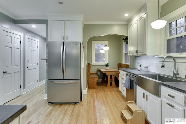 kitchen with a sink, dark countertops, light wood finished floors, and stainless steel appliances