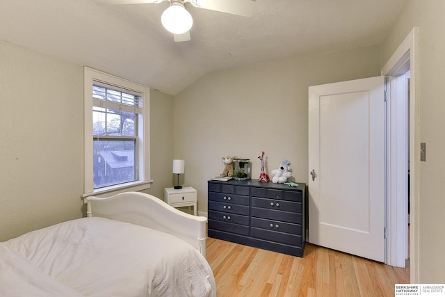 bedroom with vaulted ceiling, a textured ceiling, ceiling fan, and wood finished floors