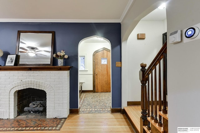 foyer featuring baseboards, stairway, ornamental molding, a fireplace, and wood finished floors