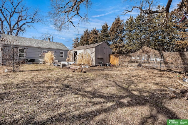 view of yard featuring fence, an outdoor structure, and a shed