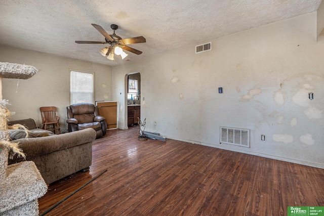 unfurnished living room with visible vents, arched walkways, a textured ceiling, and wood-type flooring