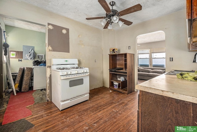 kitchen with a sink, a textured ceiling, white gas stove, and dark wood-style flooring