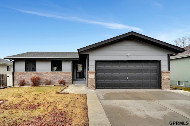 view of front of property with brick siding, an attached garage, a front lawn, roof with shingles, and driveway