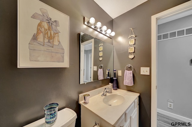 bathroom with baseboards, toilet, and vanity