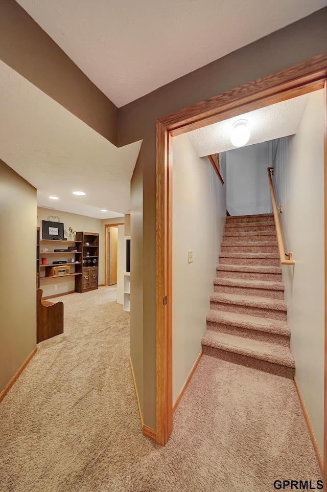 stairway featuring baseboards and carpet