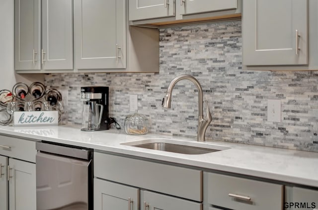 kitchen featuring decorative backsplash, light countertops, and a sink