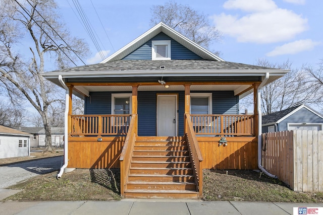 view of front of property featuring a porch, roof with shingles, and fence