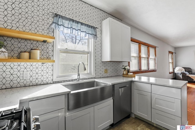 kitchen with backsplash, open floor plan, appliances with stainless steel finishes, a peninsula, and a sink