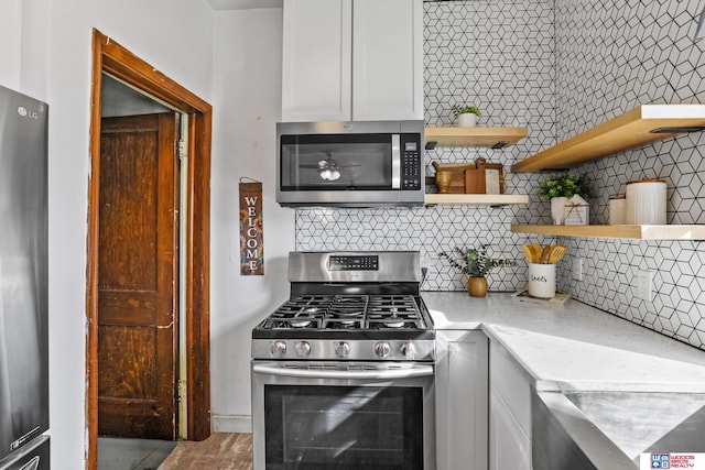 kitchen featuring light stone countertops, open shelves, decorative backsplash, white cabinets, and appliances with stainless steel finishes