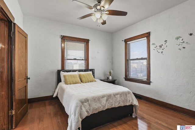 bedroom featuring baseboards, multiple windows, and hardwood / wood-style flooring