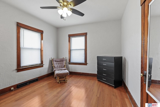 living area featuring a wealth of natural light, visible vents, baseboards, and light wood-style floors