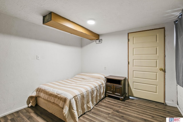 bedroom with dark wood finished floors, a textured wall, baseboards, and a textured ceiling